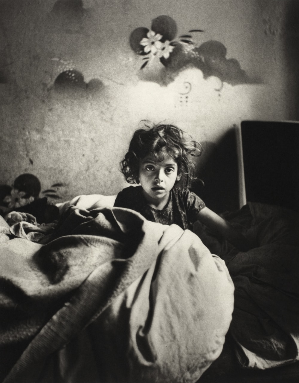 Roman Vishniac, 'Sara, sitting in bed in a basement dwelling, with stenciled flowers above her head, Warsaw', ca. 1935–37. © Mara Vishniac Kohn, courtesy International Center of Photography. On display at The Photographers’ Gallery