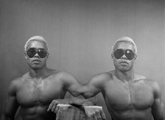 A black and white portrait of two black men with bleached hair and sunglasses