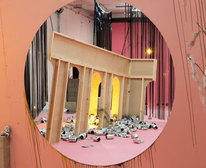 pink and green carpet, cast concrete objects, timber and hardboard structures, strip lights, fans, tin cans, video tape curtains, video tape, flowers, feathers, rubber, cast metal objects, photo structure and timber frame. Flare Audio speakers